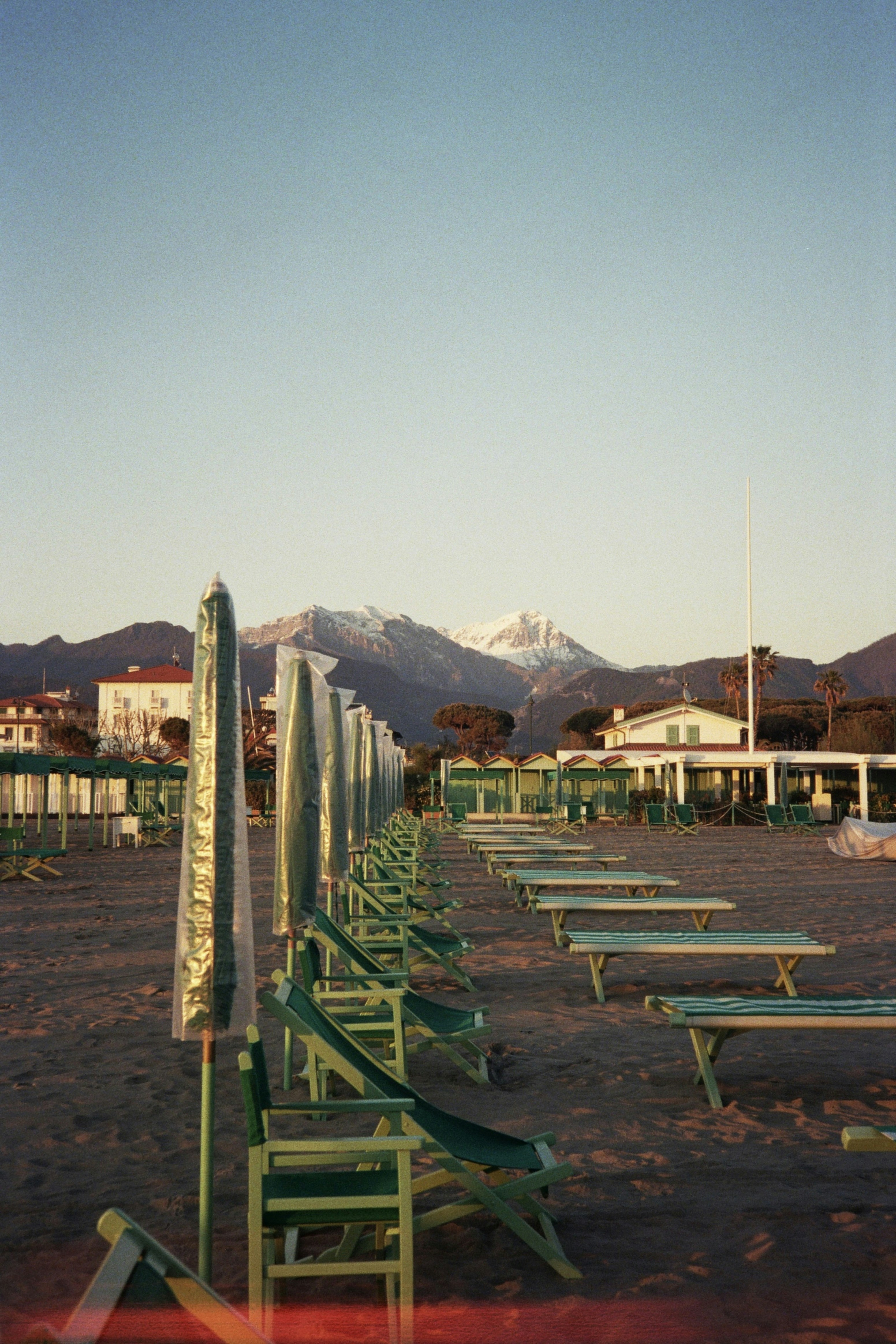 A row of beach chairs sitting on top of a sandy beach
