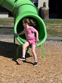 A little girl playing in a green slide