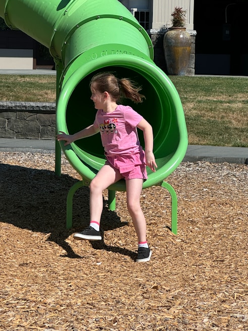 A little girl playing in a green slide