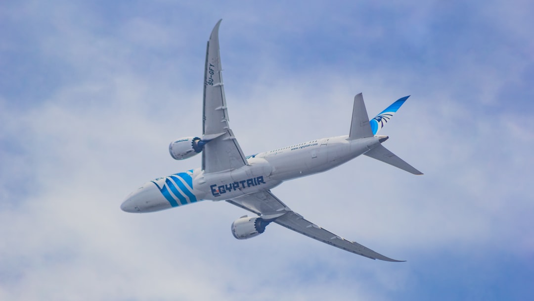 A large passenger jet flying through a cloudy blue sky, EgyptAir Boeing 787-9 Dreamliner departing from Dhaka to Cairo!