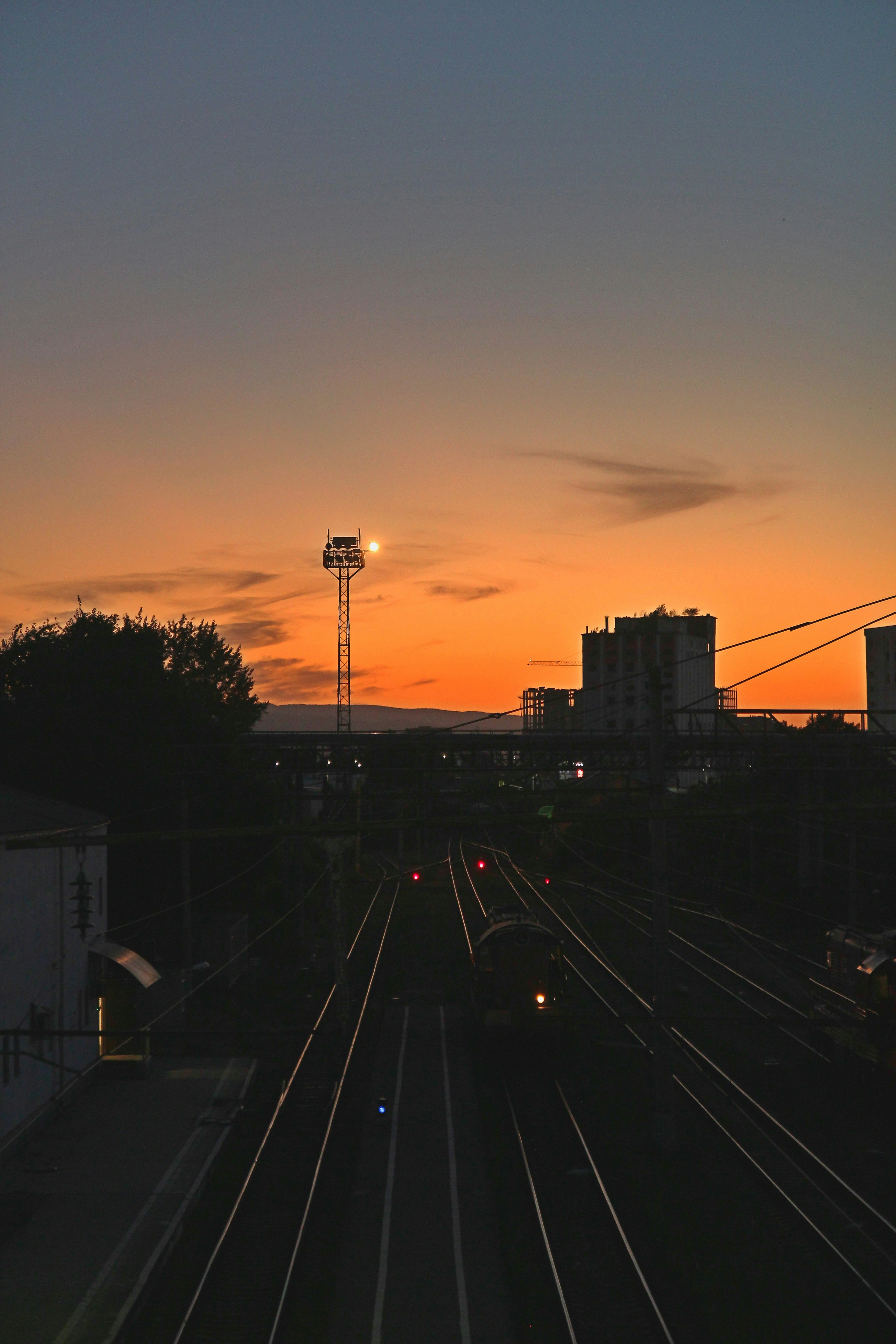 A sunset view of a train track with buildings in the background