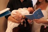 A man holding a baby while reading a book