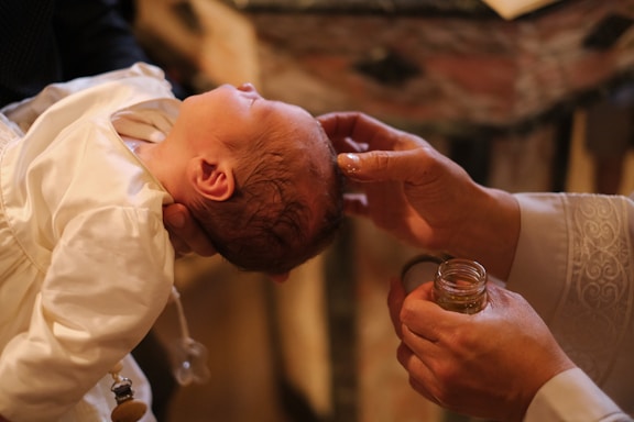 A baby is being fed a glass of wine