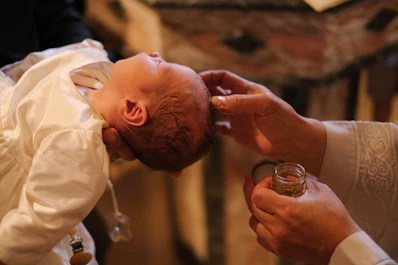 A baby is being fed a glass of wine