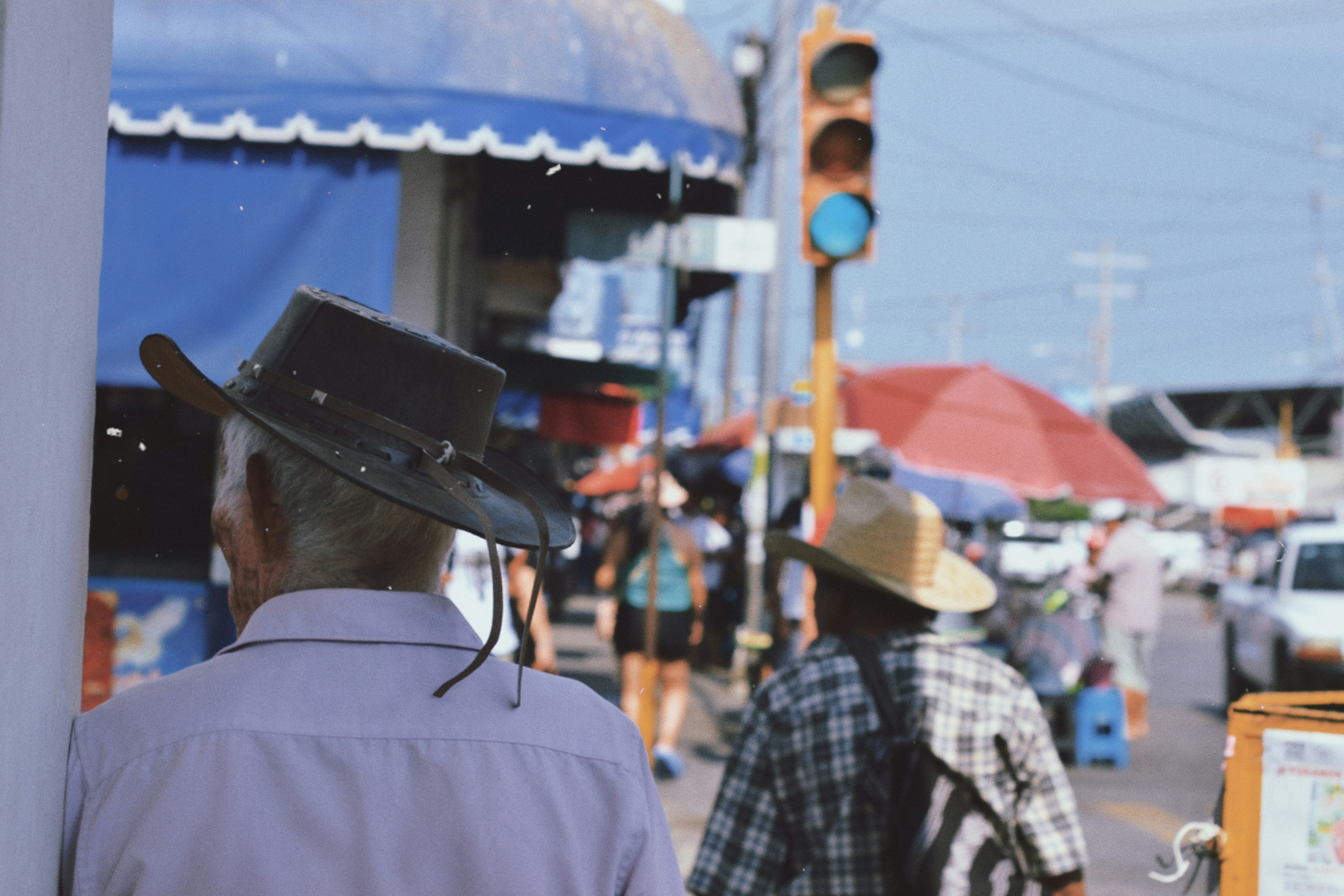 A man wearing a cowboy hat standing next to a traffic light