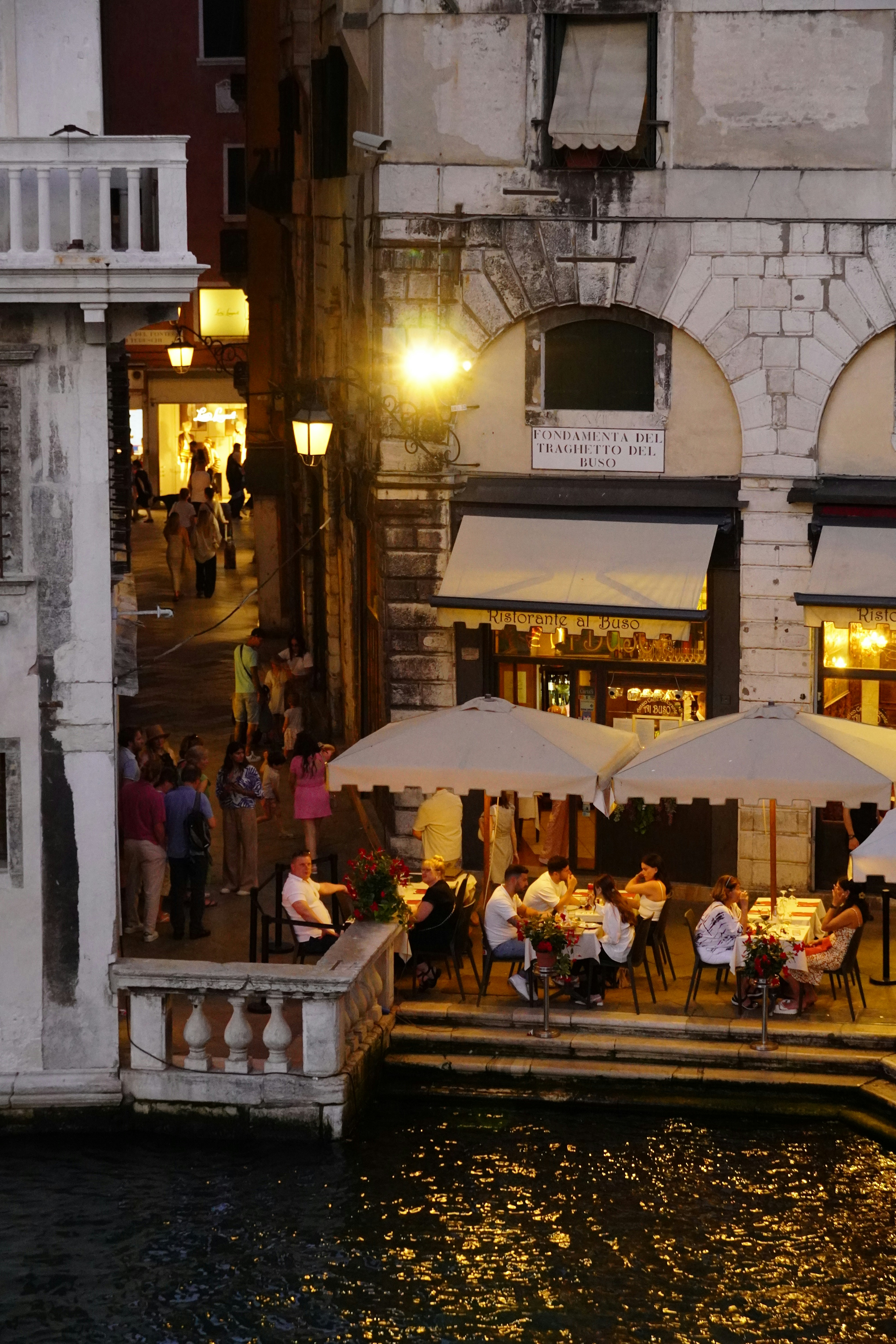A group of people sitting at tables next to a body of water