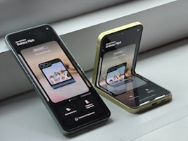 Two cell phones sitting next to each other on a window sill
