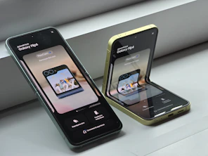 Two cell phones sitting next to each other on a window sill