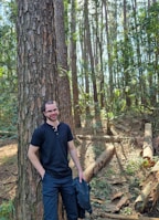 A man standing next to a tree in a forest