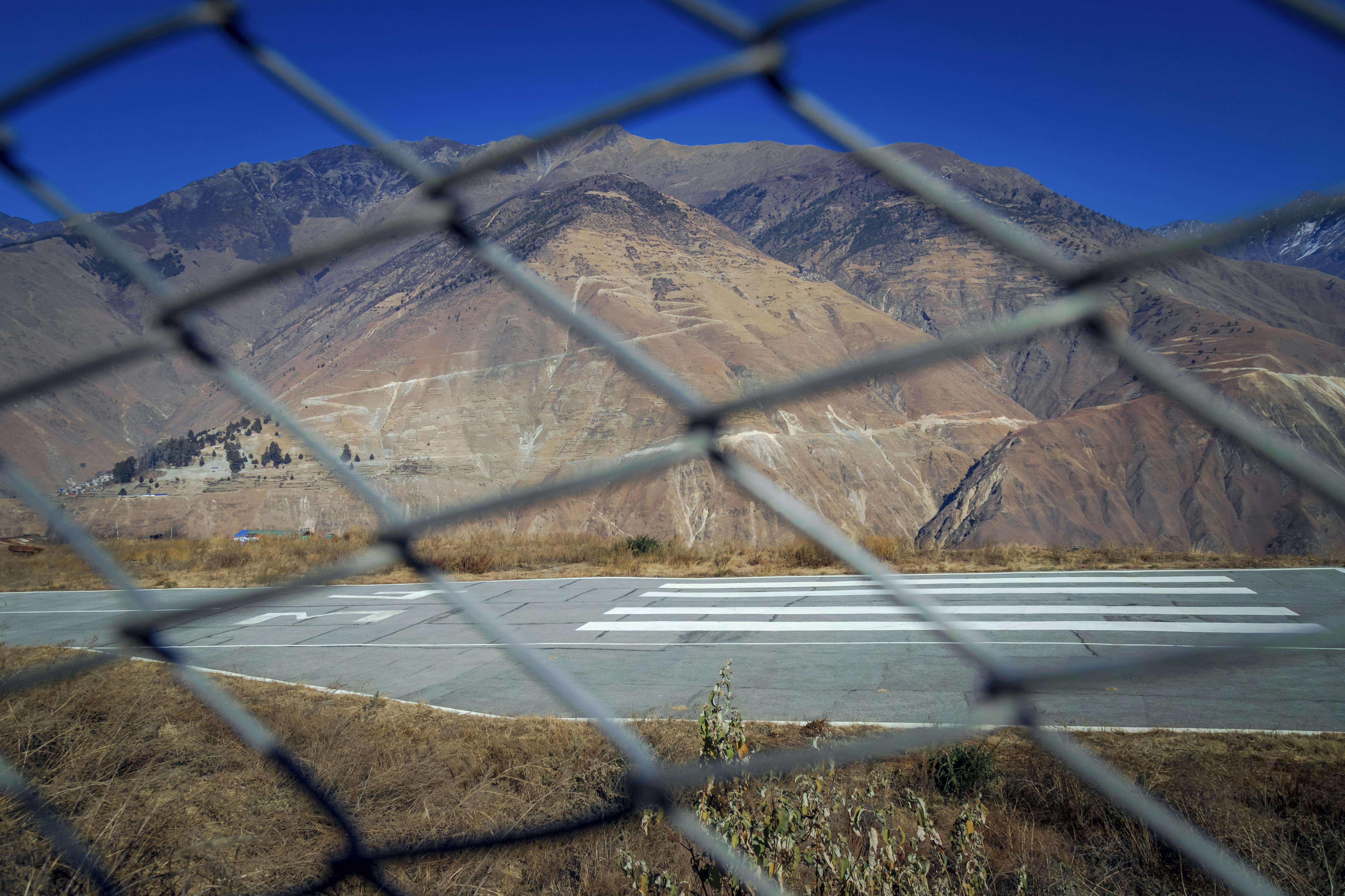 A view through a chain link fence of an airport runway (Photo by ashok acharya on Unsplash)