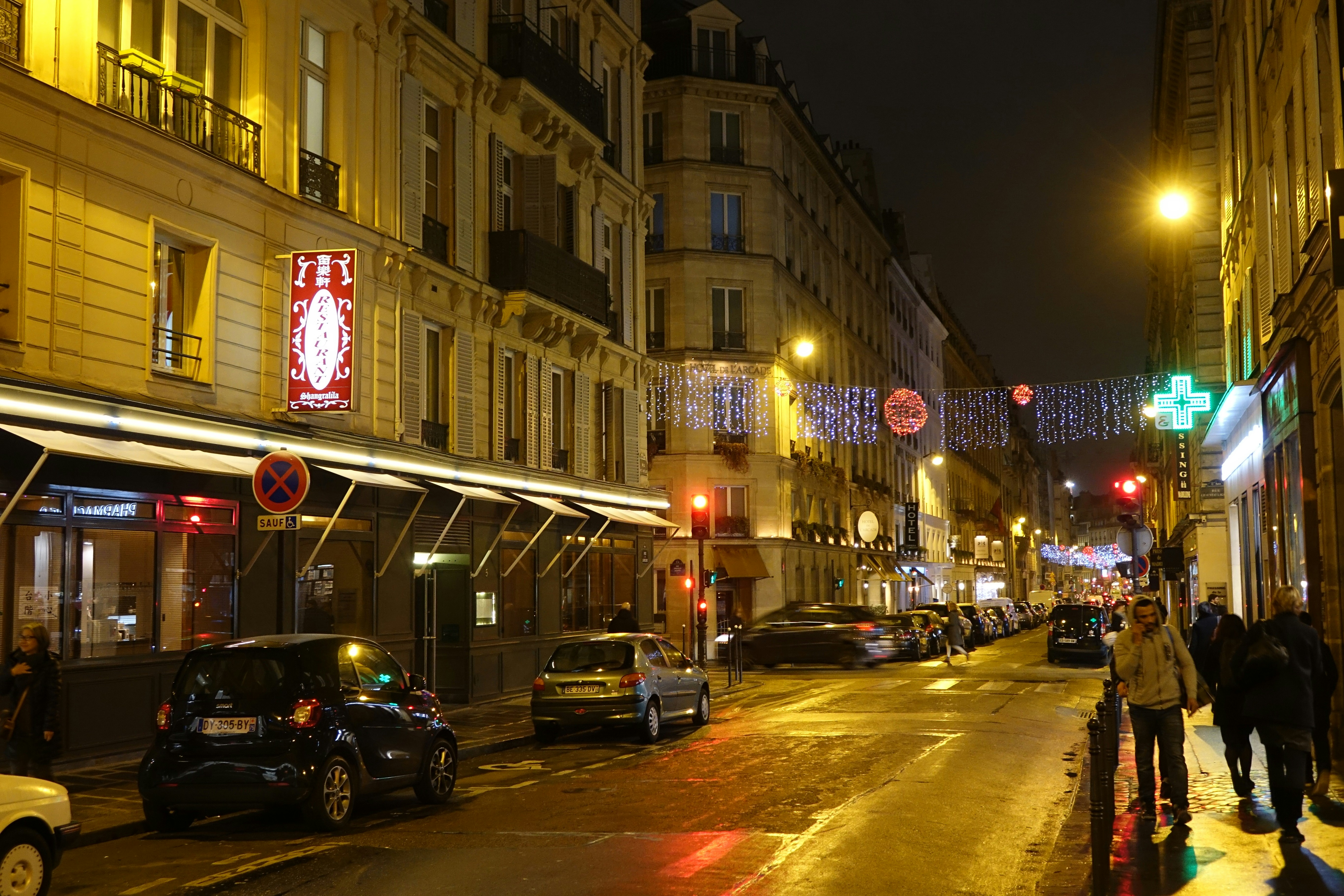 A city street at night with cars parked on the side of the street