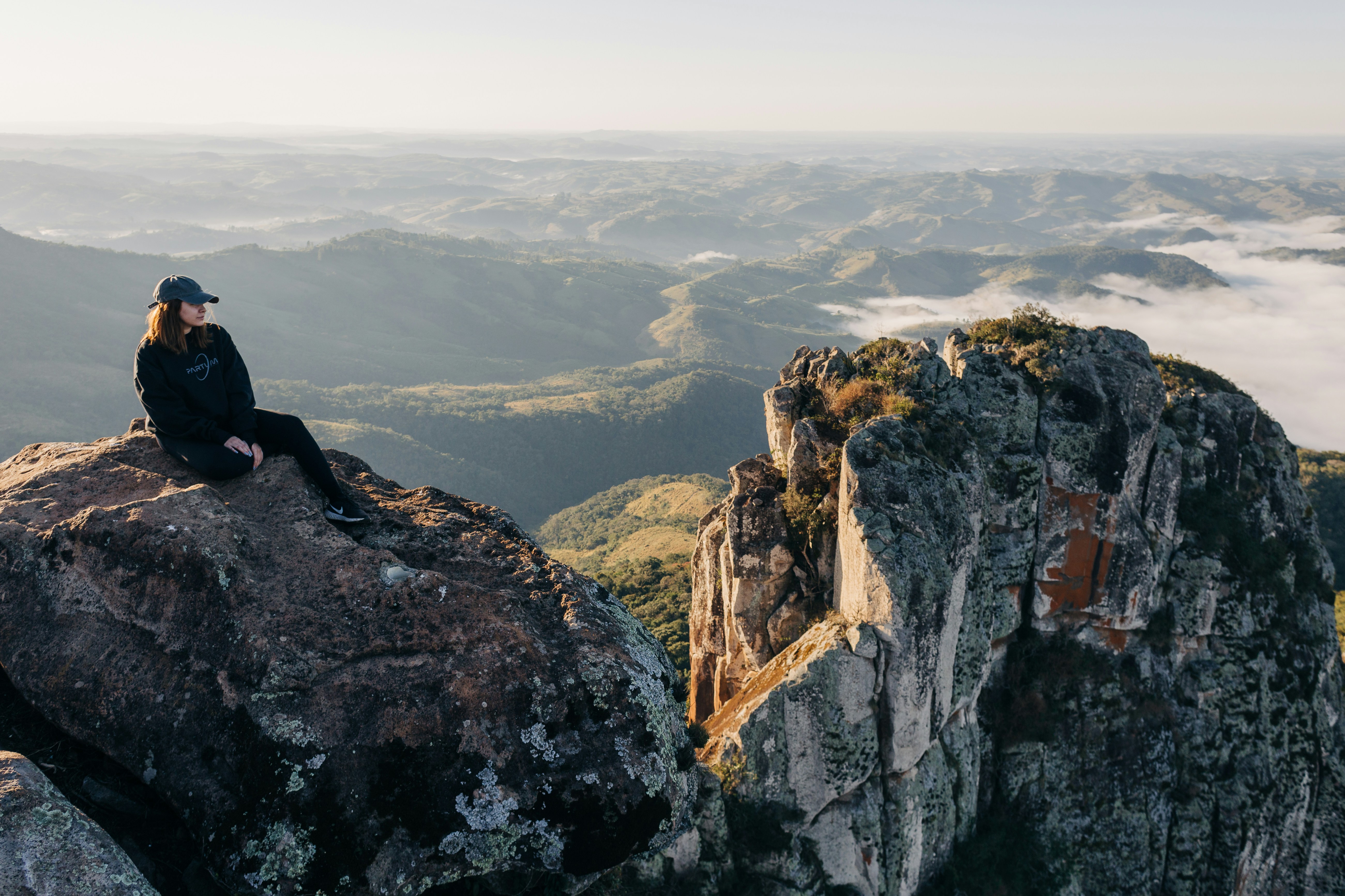 A woman sitting on top of a large rock