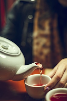 A person pouring tea into a white teapot