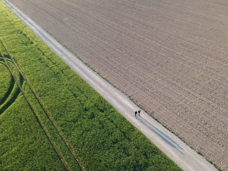 An aerial view of a farm field with a tractor in the middle of it