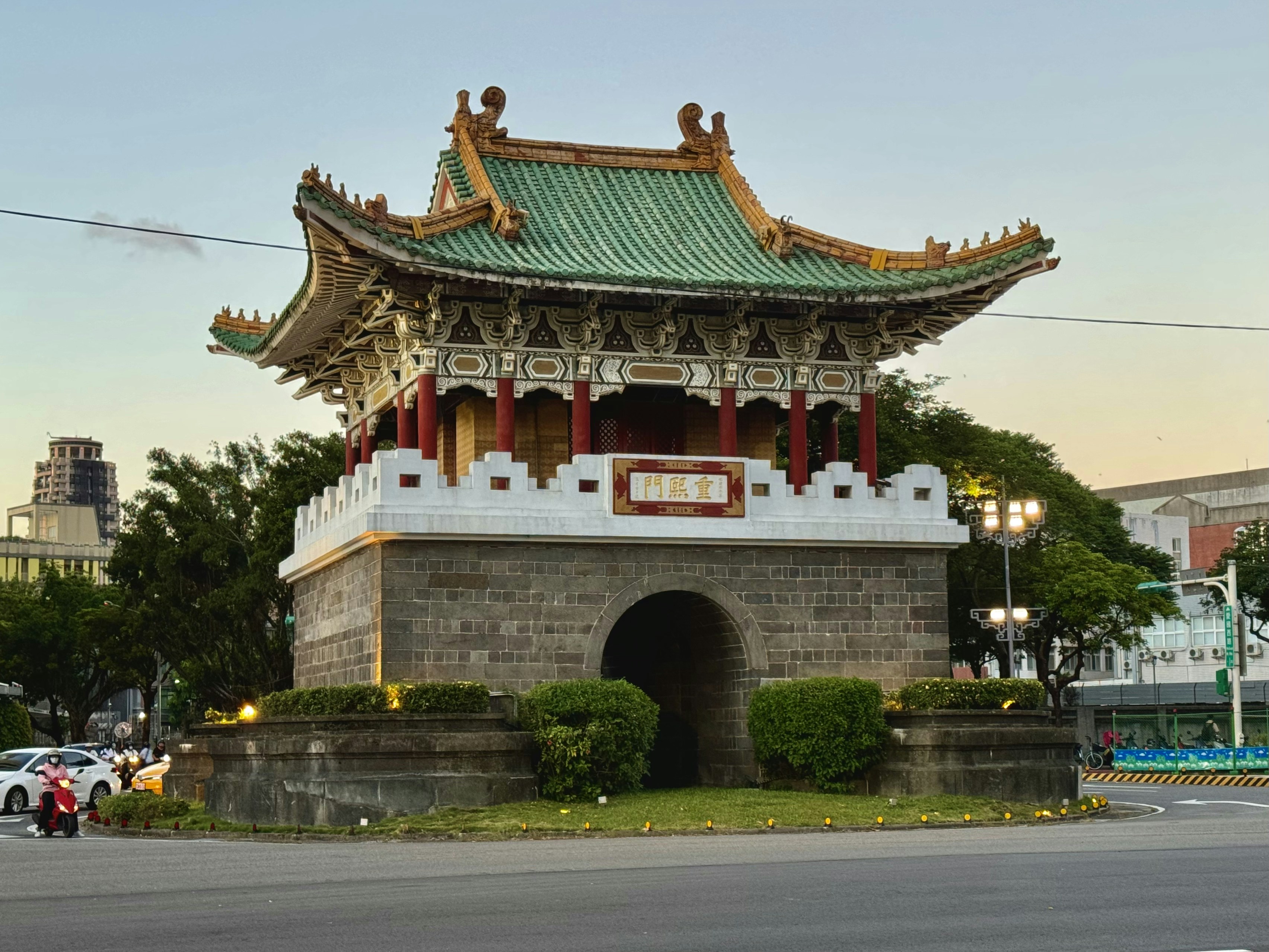 A tall building with a green roof on top of a street