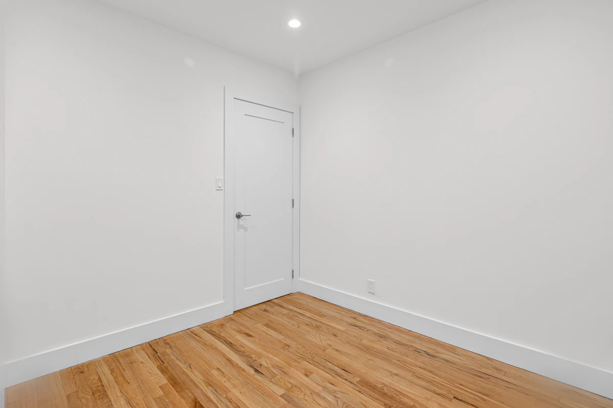 Bright empty room with warm wide-plank hardwood and large windows.