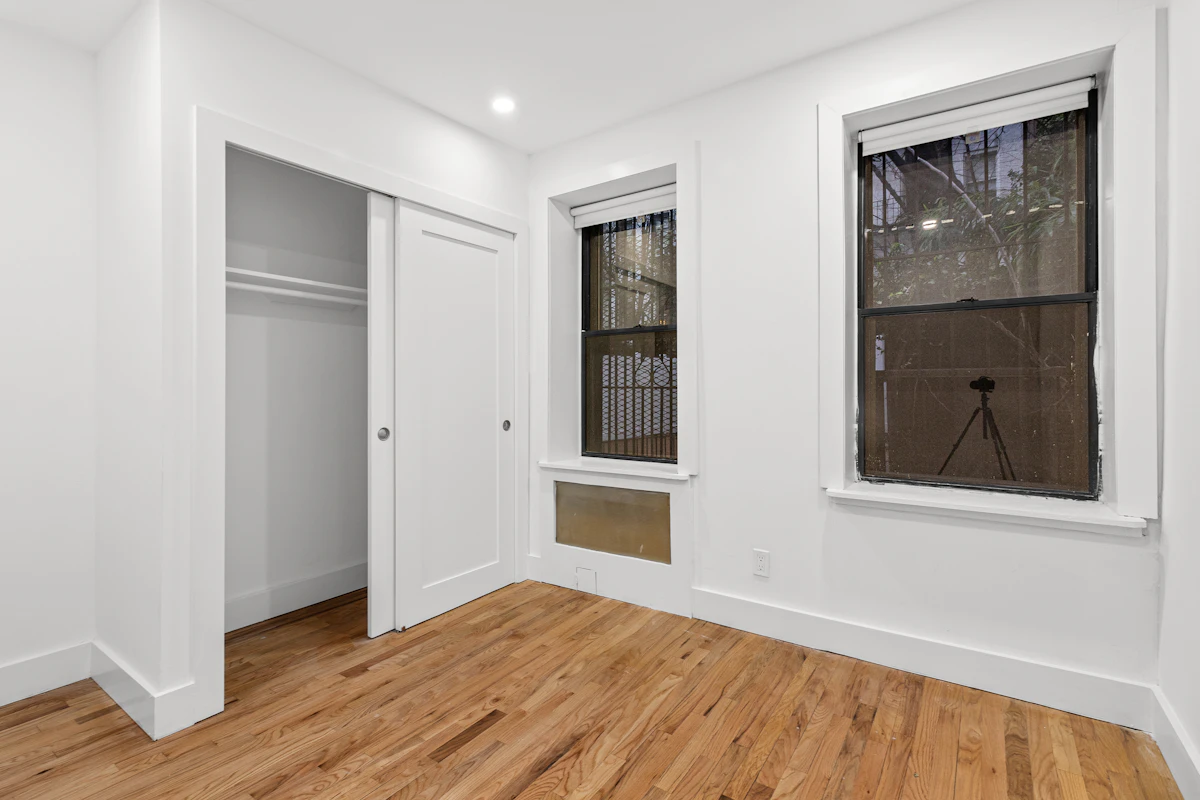 Empty room with a closet alcove over warm oak hardwood.