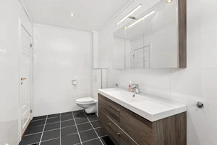 A bathroom with a toilet, sink, and mirror