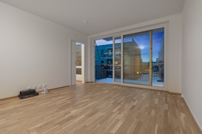 An empty room with large windows and a hard wood floor