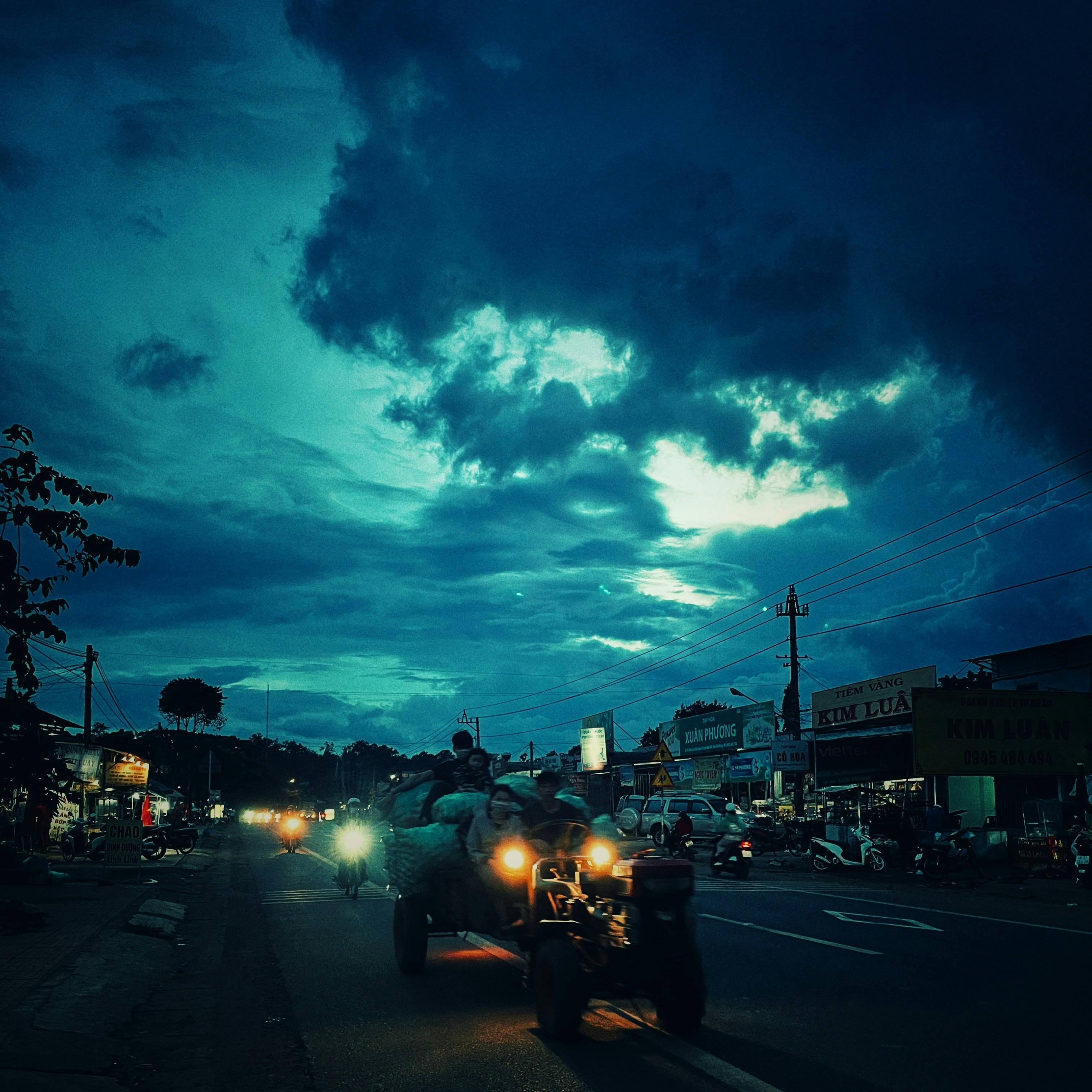 Delivery truck on road in early morning light, dark overcast sky, commercial vehicle loaded with goods for delivery