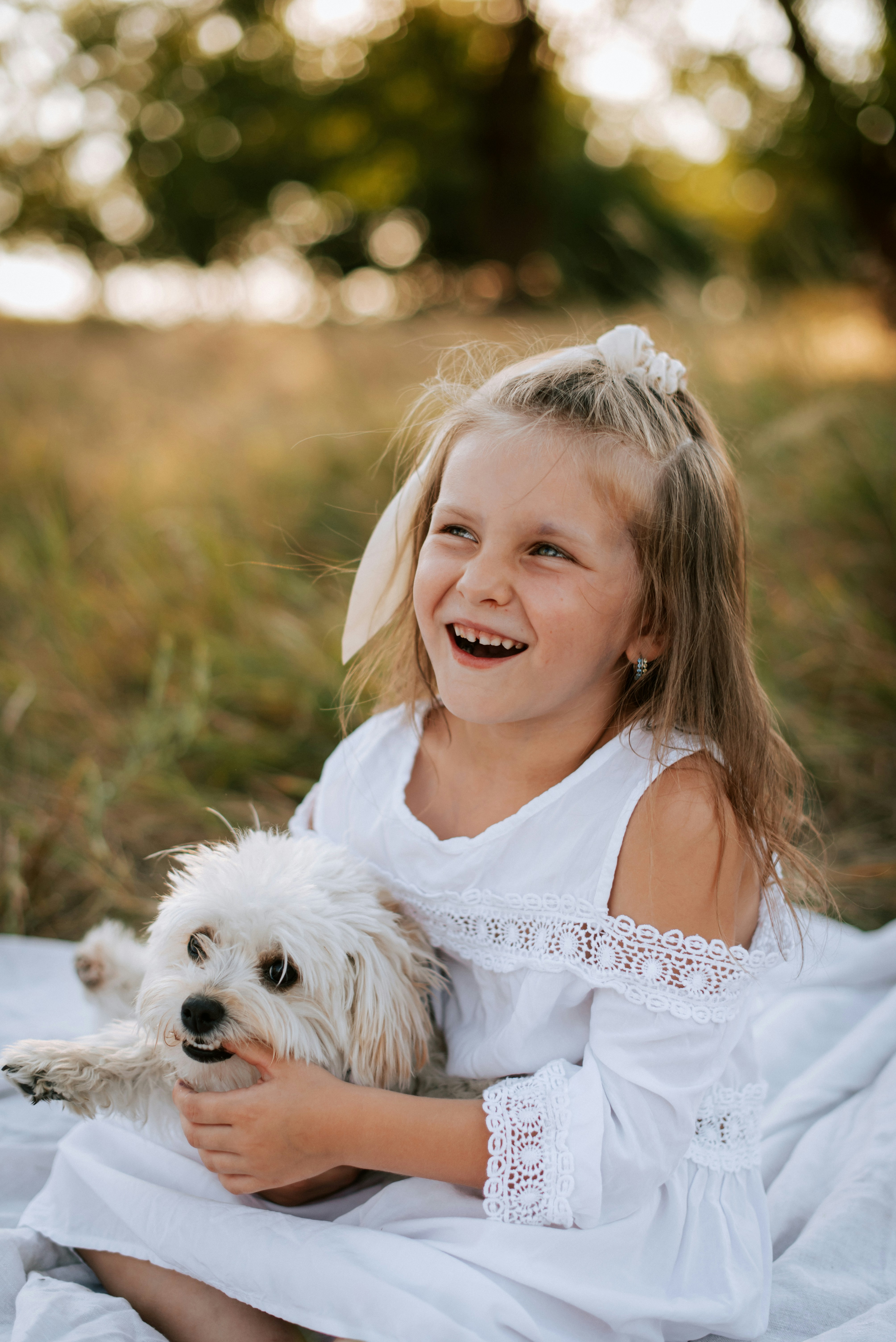 Child hugging a large fluffy white dog in a garden, both looking happy and content