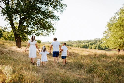 A family walking through a field with a dog