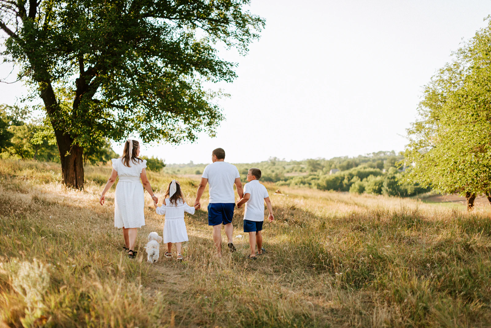 A family walking through a field with their dog