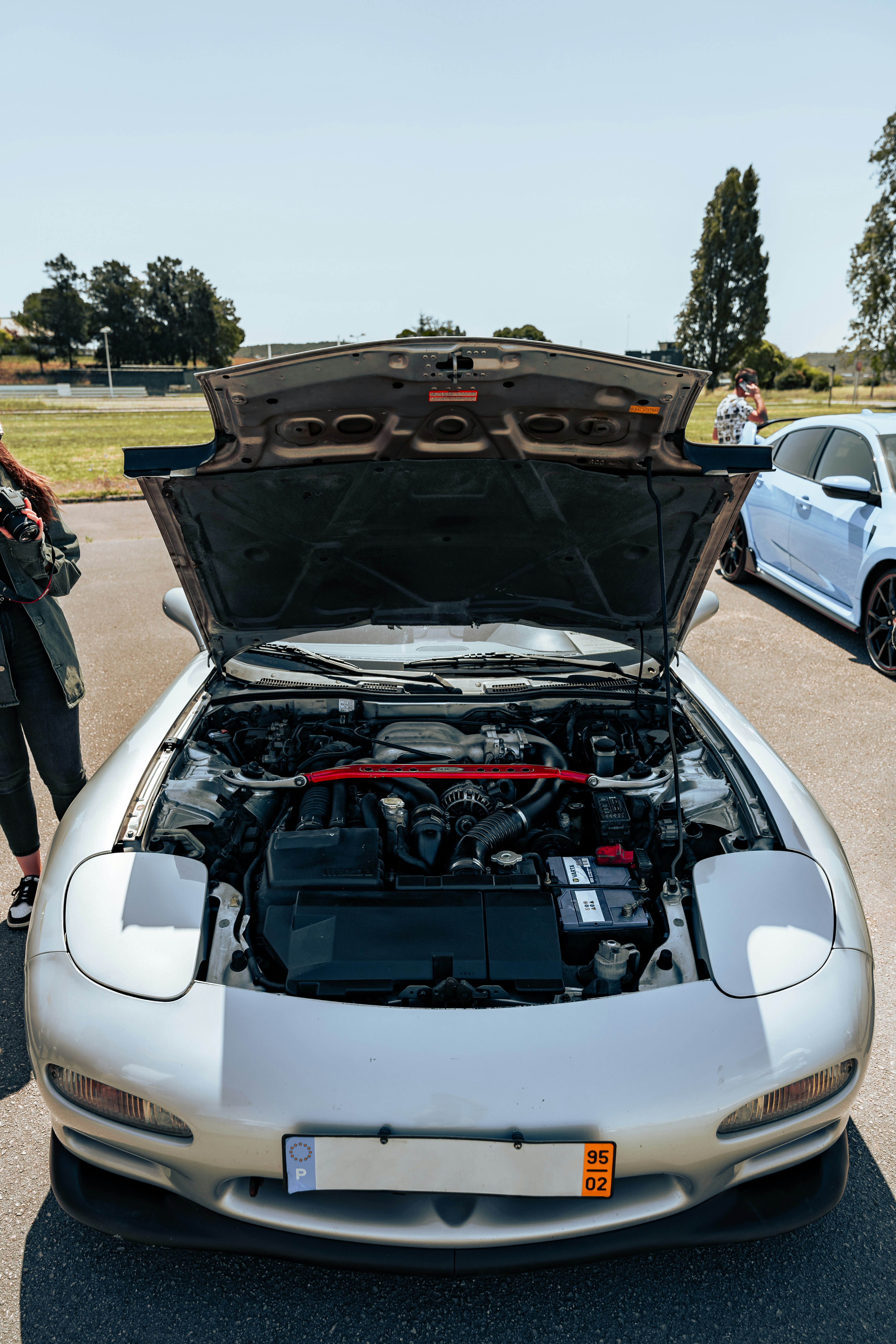 Um carro esportivo prateado com o capô aberto