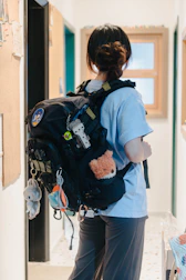 A woman with a backpack is standing in a hallway