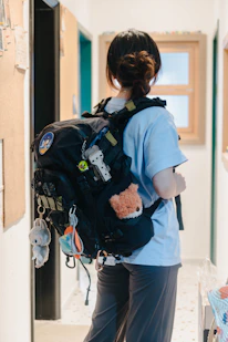 A woman with a backpack is standing in a hallway