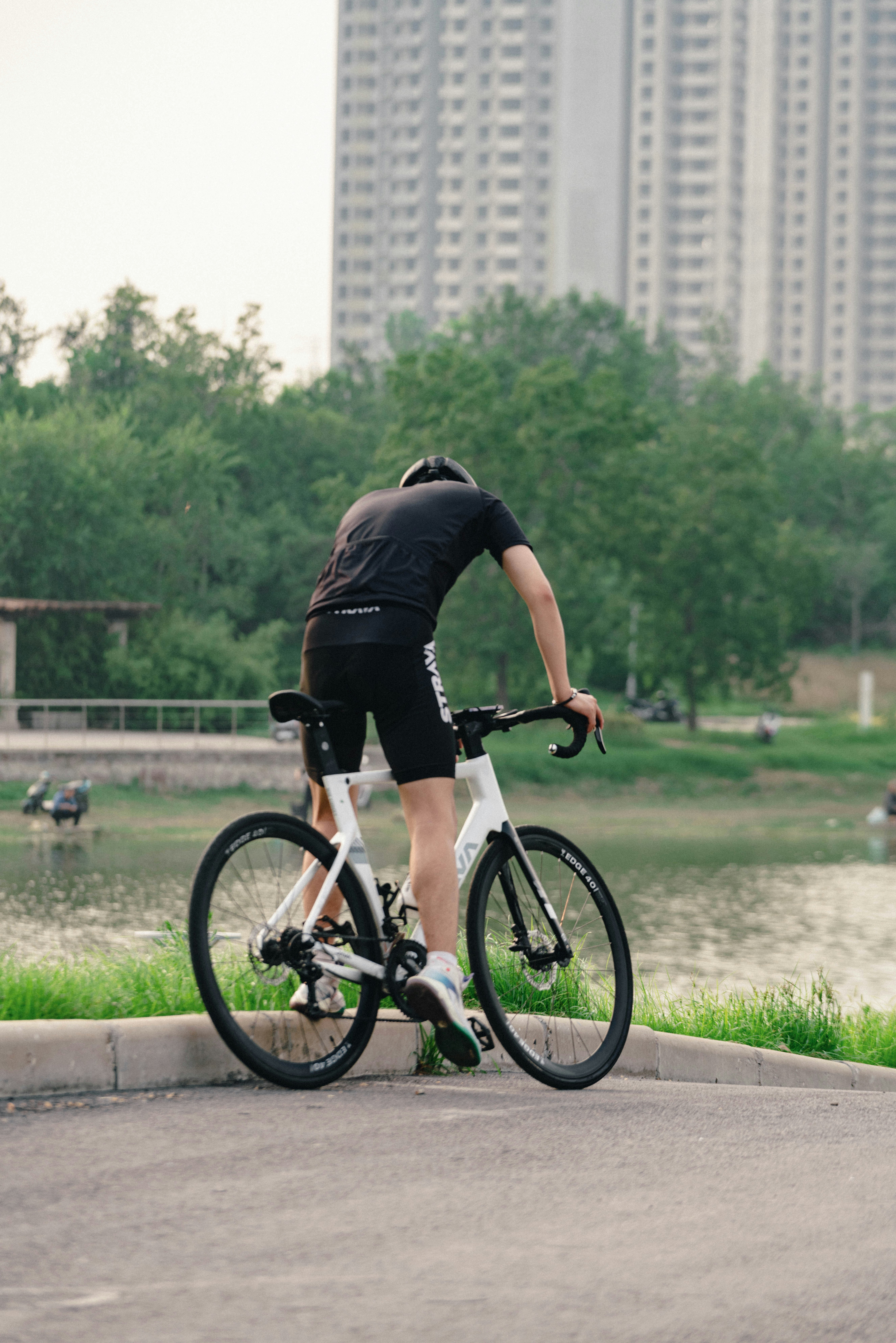 A man riding a bike down a street next to a lake