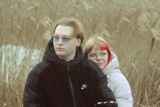 A man and a woman standing in a field of tall grass