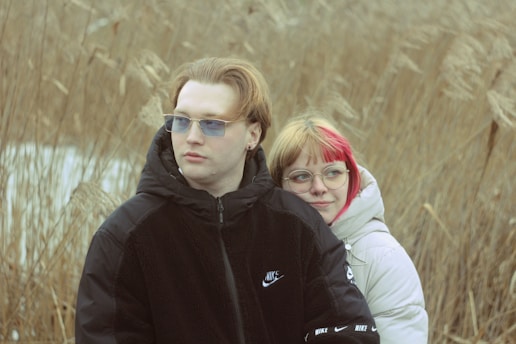 A man and a woman standing in a field of tall grass