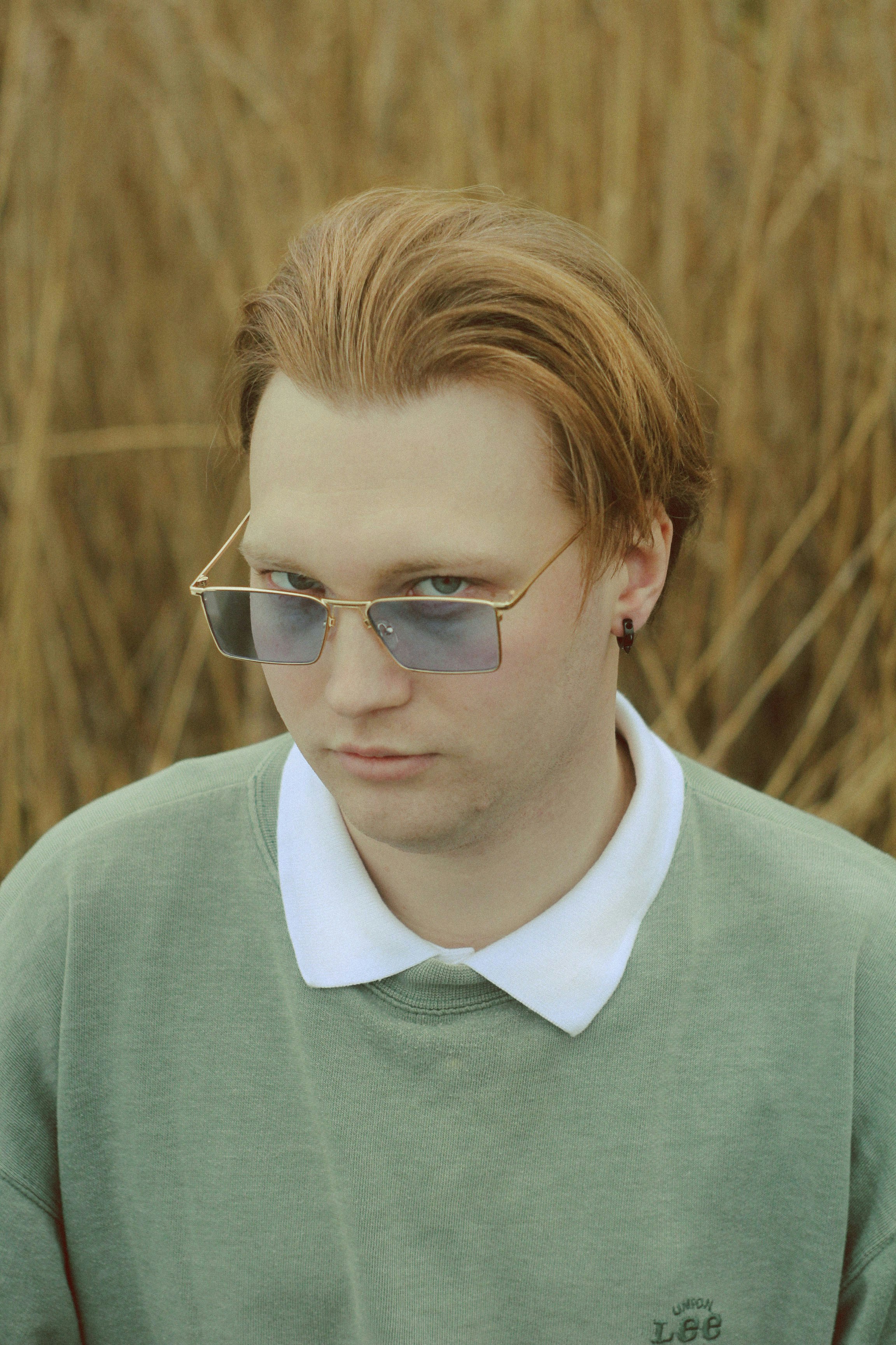 A man wearing sunglasses and a green sweater