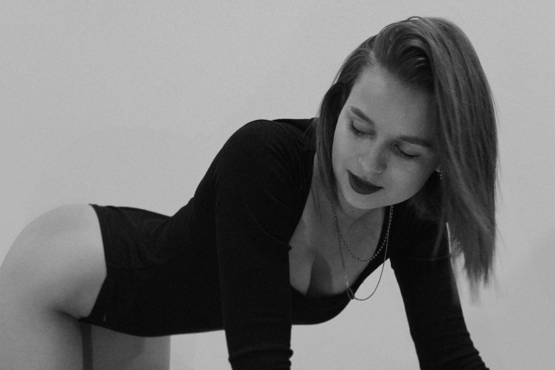 A woman in a black dress leaning on a wall