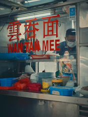 A man standing behind a counter filled with food