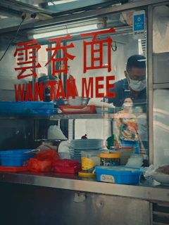 A man standing behind a counter filled with food
