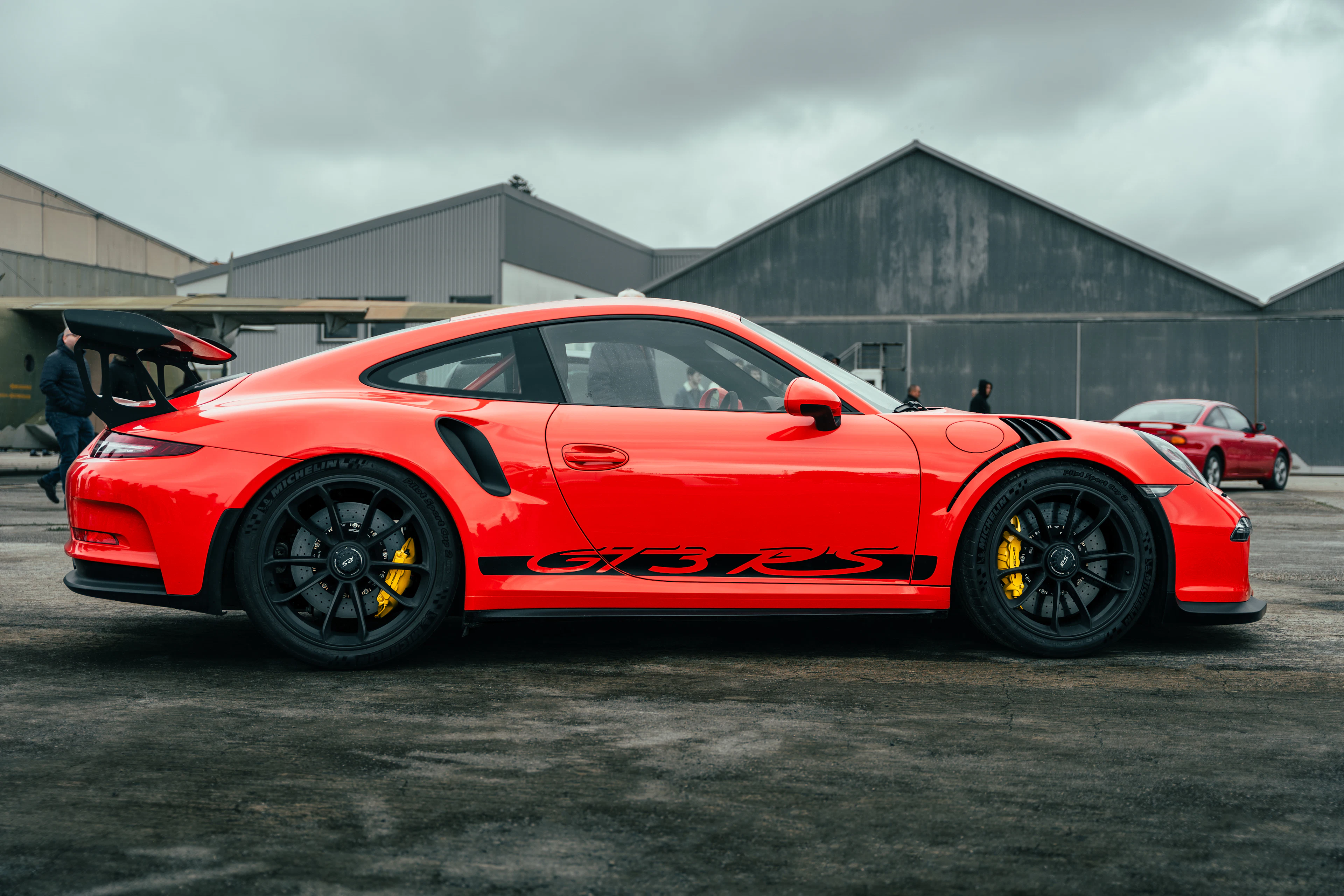 Red Porsche 911 GT3 RS parked in front of a hangar
