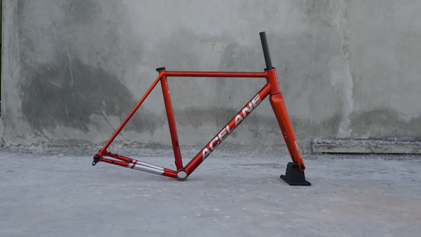 A red bicycle leaning against a concrete wall