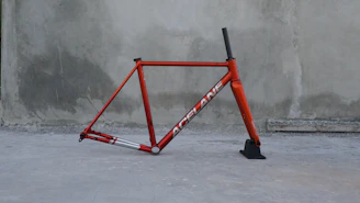 A red bicycle leaning against a concrete wall