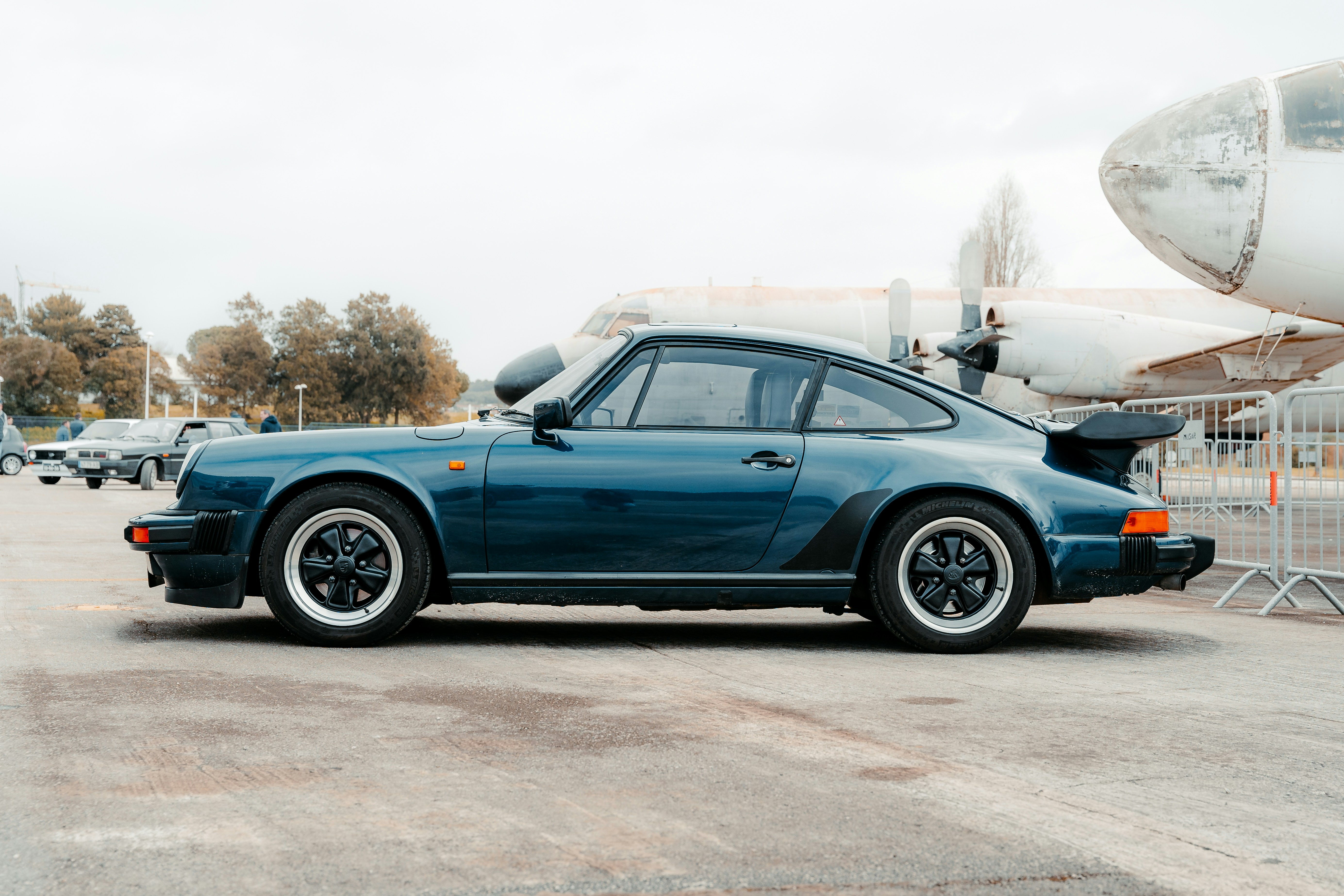 Ein blauer Sportwagen, der vor einem Flugzeug geparkt ist