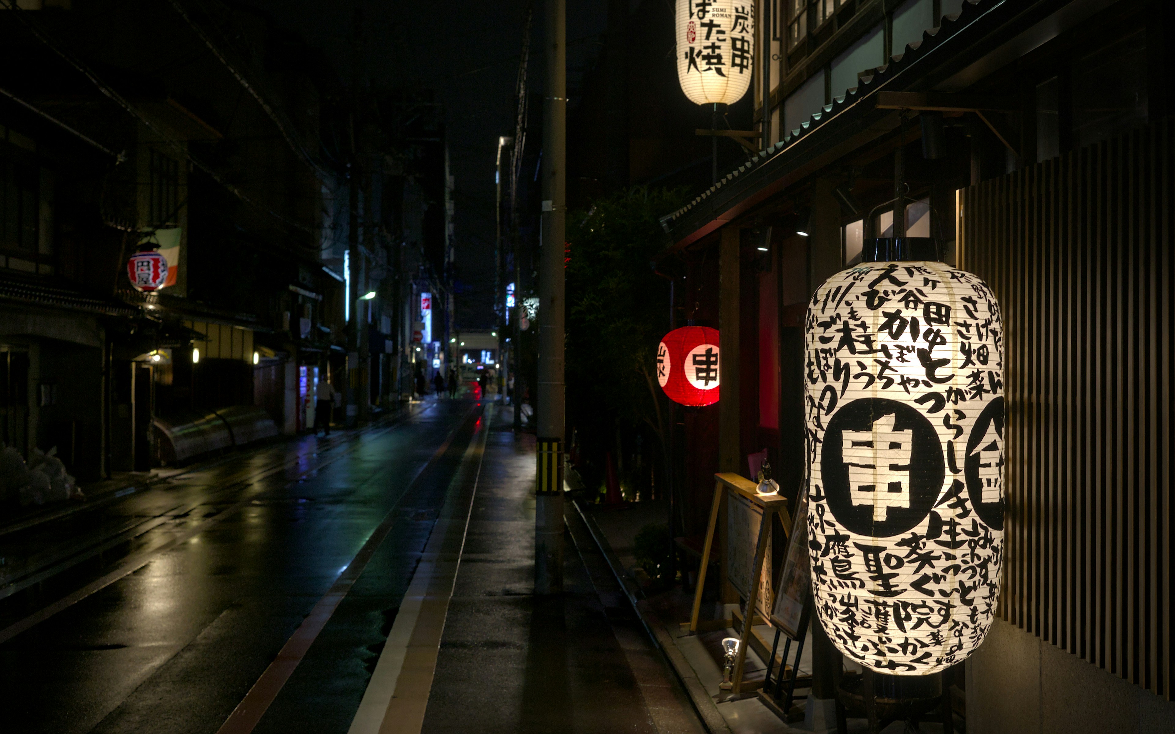 A city street at night with a lit up clock