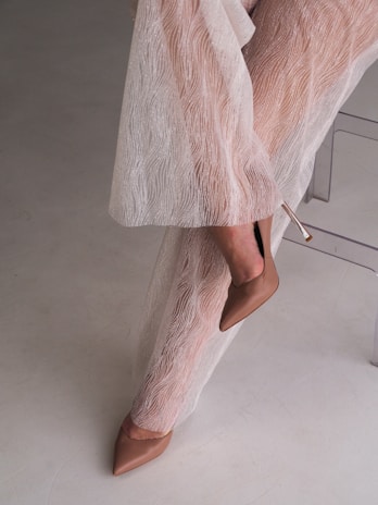 A woman in a white dress leaning against a wall