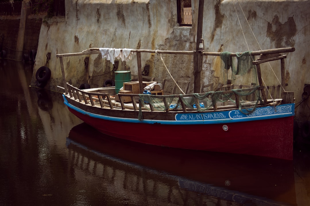 A red and blue boat in a body of water, Wooden boat stationed on the port.