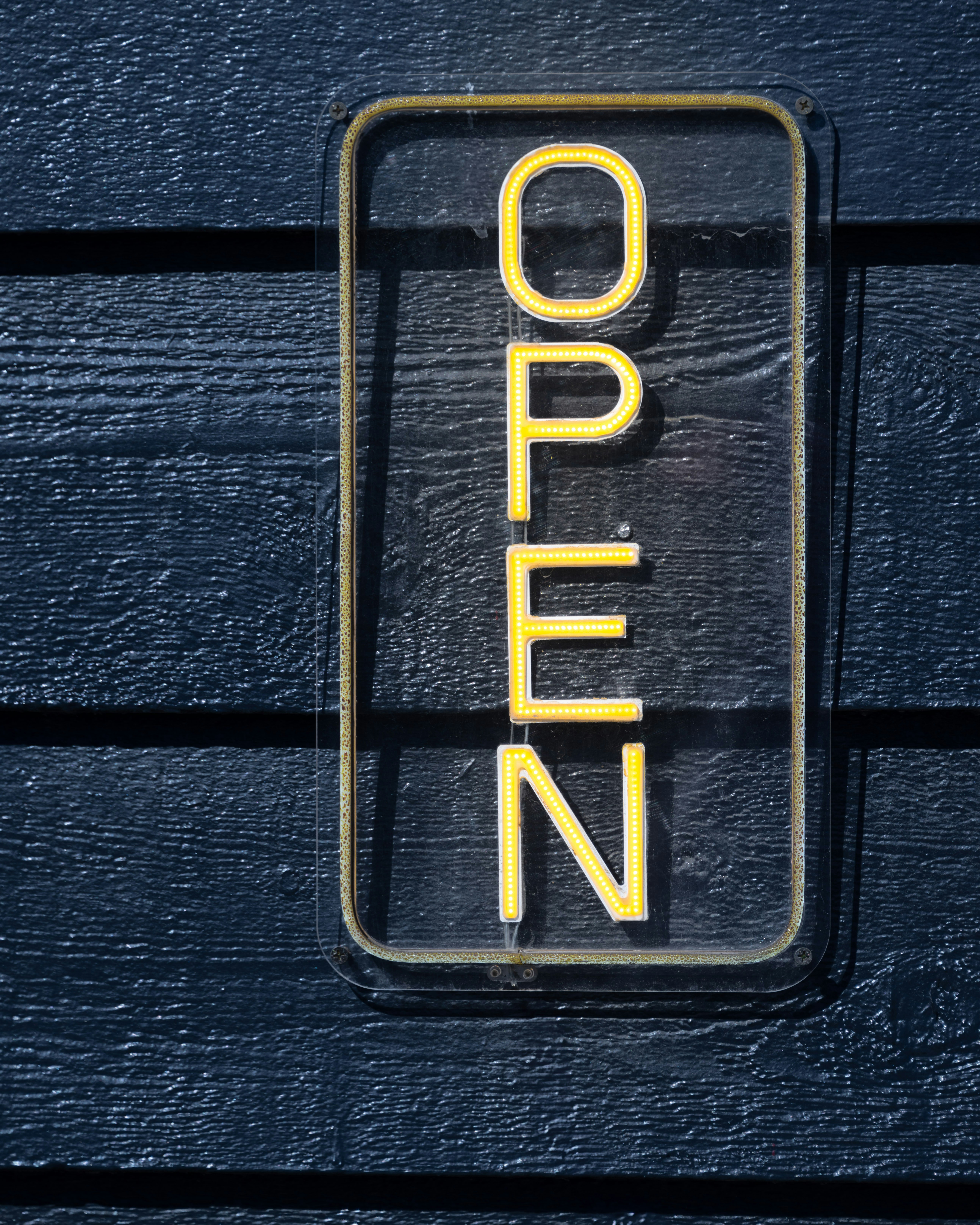 A sign that reads open on a wooden wall