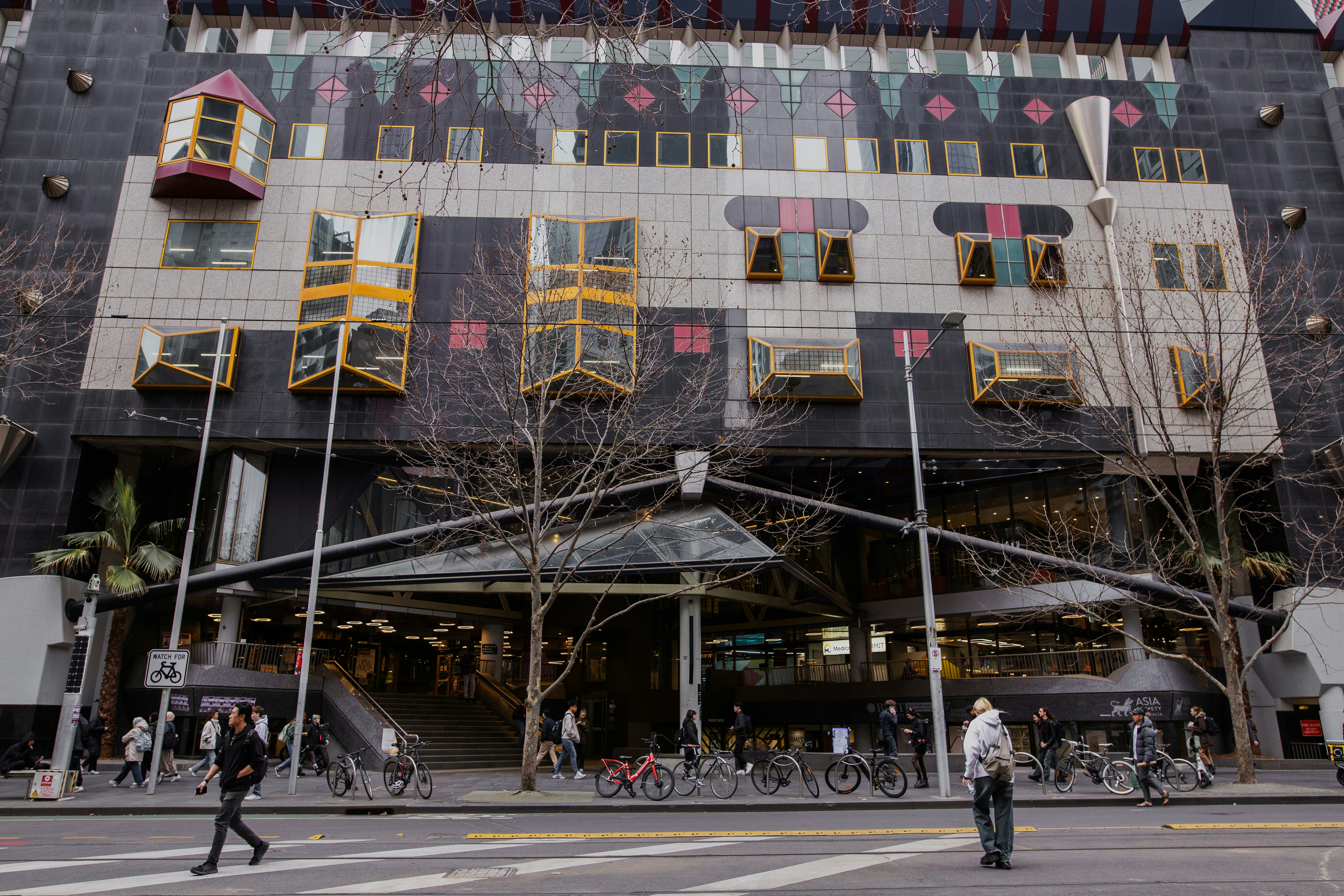 A large building with a lot of windows and people crossing the street