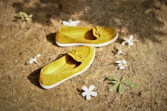A pair of yellow shoes sitting on top of a dirt field