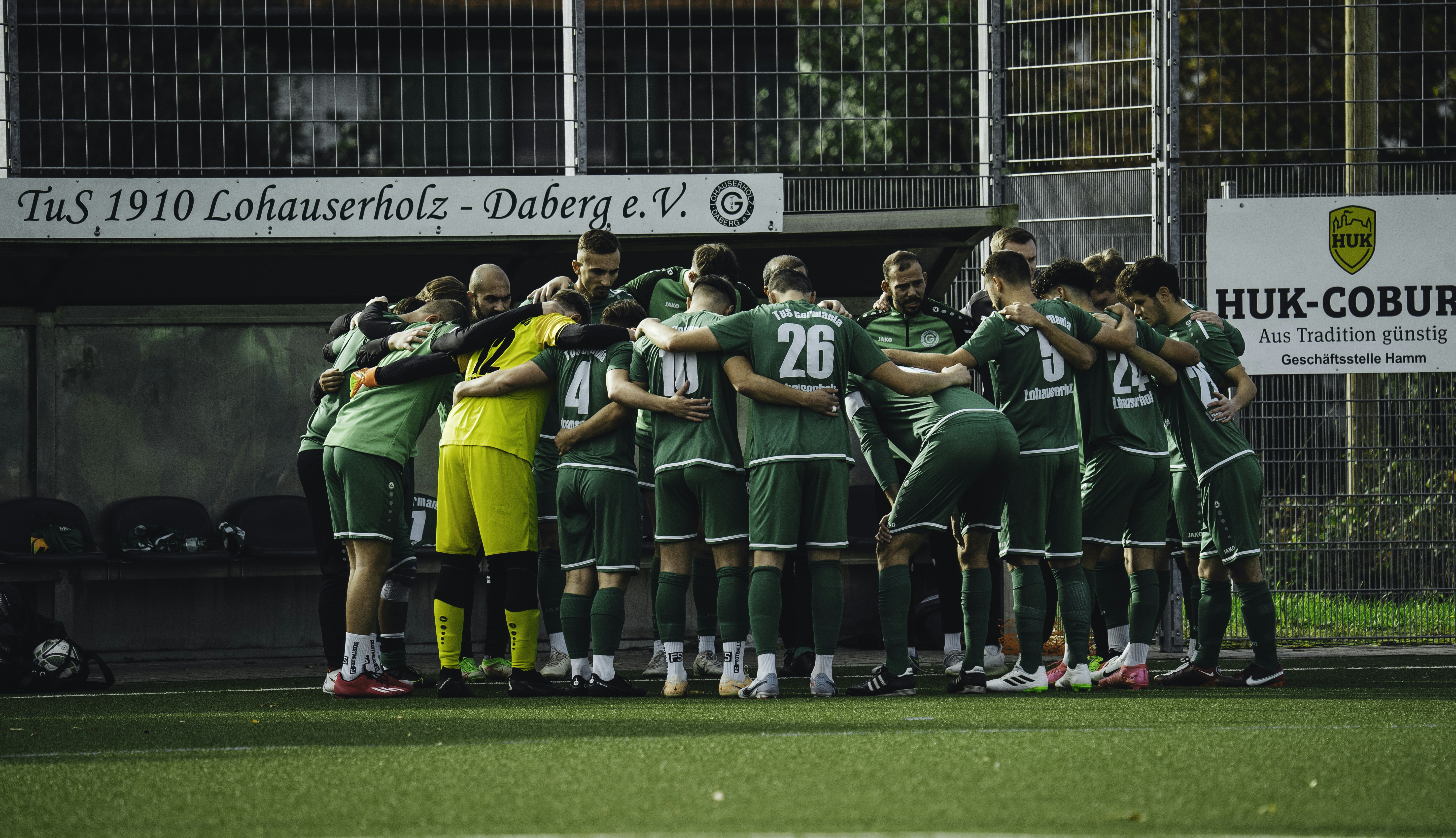 A group of soccer players huddle together on the field