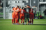 A group of soccer players huddle together on the field