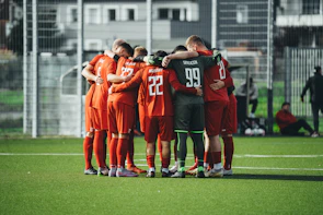 A group of soccer players huddle together on the field